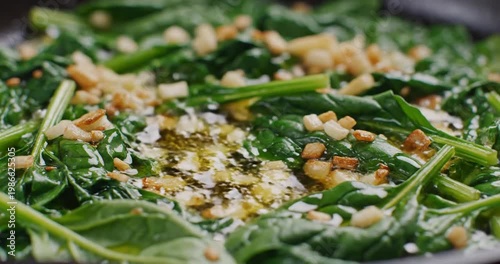 Freshly cooked spinach with garlic and crispy toppings in a pan, showcasing vibrant colors