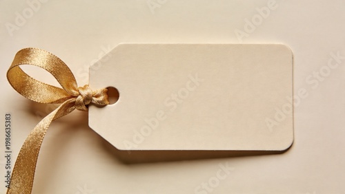 features a rectangular, beige-colored tag with a smooth, matte finish. The tag has a single, rounded corner and a small hole near the top left corner, through which a golden, textured ribbon is loope