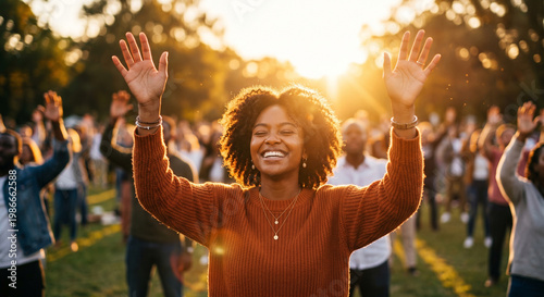 Joyful diverse woman with raised hands during outdoor worship at sunset.