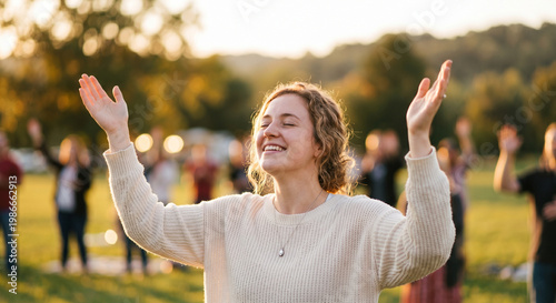 Joyful diverse woman with raised hands during outdoor worship at sunset.
