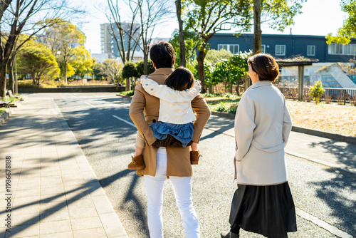Young Japanese Family with Child on a Piggyback Ride Walking Through a Sunny Park