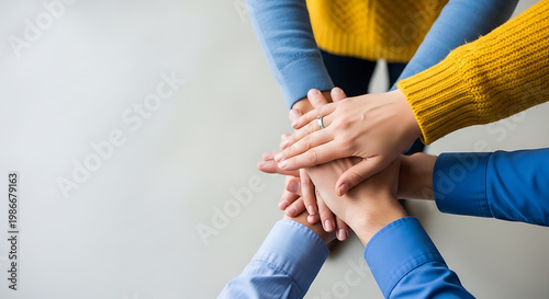 Diverse team hands stacked together in unity, showing collaboration and teamwork on a bright, clean background.