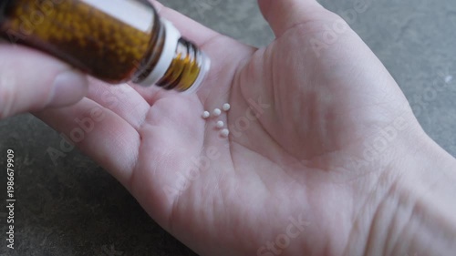 Taking out homeopathic pills out of a glass jar onto palm
