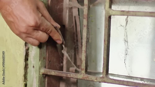 Close Up of Person Hand Opening Old Dusty Glass Window with Rusty Metal Trellis