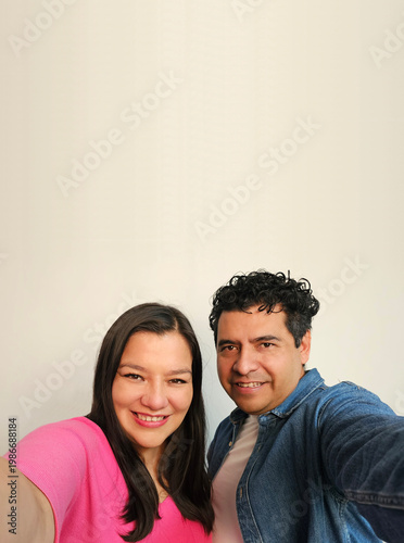 Latino man and woman in their 40s show their love to celebrate Valentine's Day and their anniversary with kisses and hugs, laughing and smiling