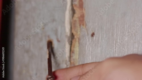 Close Up of Person Locking Old Wooden Door Using a Rusty Nail as a Traditional Bolt