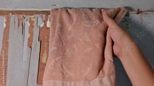 Close Up of Hand Pulling an Orange Towel Stuck Between Old Wooden Door Frames