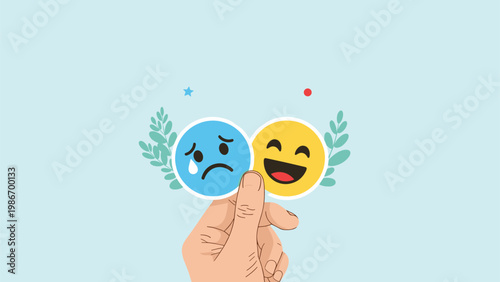 Hand holding two contrasting emoticons of a sad crying face and a happy laughing face depicts mood swings or mental health.