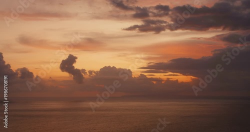 Sunset light glows through heavy clouds above the Indian Ocean at twilight