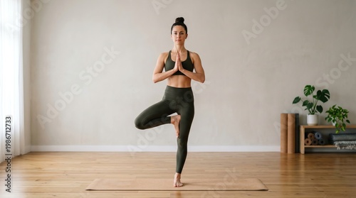 woman balancing on one leg in yoga pose, studio setting, clean composition.