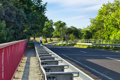 Empty Country Road Bridge with Red Railing and Guardrail in Rural Landscape