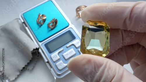 Gemologist jeweler evaluates the value and purity of yellow stones at a pawn shop.