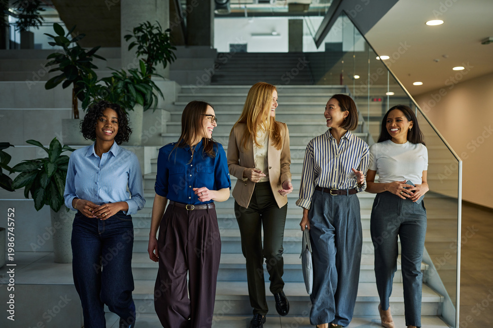 Fototapeta premium Diverse businesswomen walking, talking, and smiling in office building