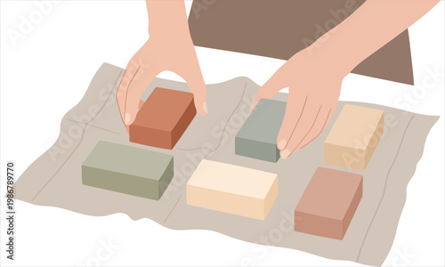 Hands arranging colorful handmade soap bars on a cloth surface