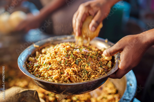 Indian street vendor hands preparing spicy bhel puri snack with puffed rice, onions and chutneys in metal bowl, detailed food texture background with copy space