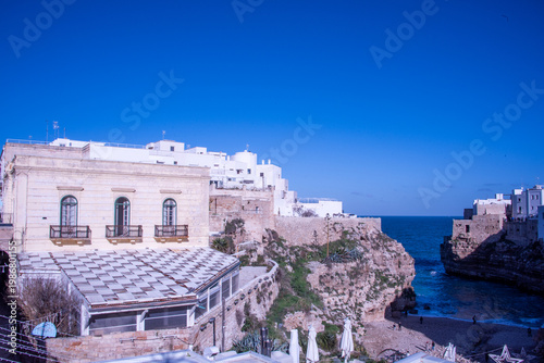 The dramatic cliffs of Polignano a Mare overlooking the Adriatic Sea, where whitewashed houses rise above crystal-clear waters along the rugged coastline.