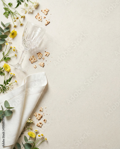 Spring floral arrangement, crystal wine glass, white linen napkin, matzo cracker crumb border