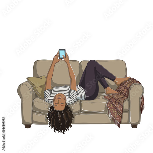 A woman lies on a couch looking at her phone with a throw blanket