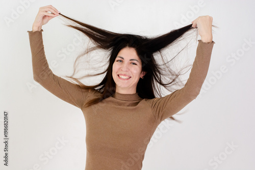 Playful Young Woman with Long Healthy Dark Hair Smiling and Posing on White Background, Beauty Concept