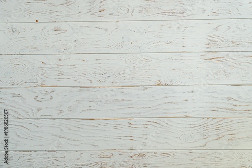 A close-up view of a textured white wooden plank surface, showcasing natural wood grain patterns and a rustic appearance.