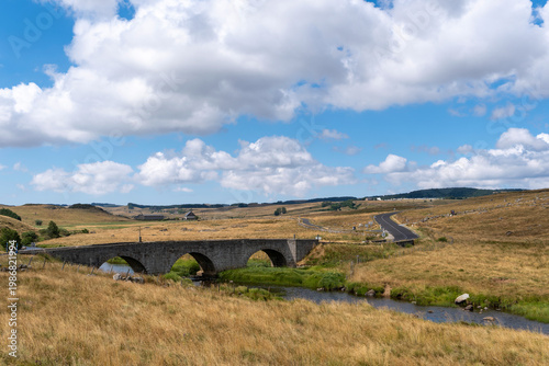 GR65 pilgrim trail crossing the Aubrac plateau, yellowed grass and dramatic cloudy sky, France