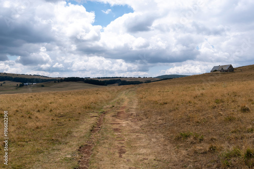 GR65 pilgrim trail crossing the Aubrac plateau, yellowed grass and dramatic cloudy sky, France