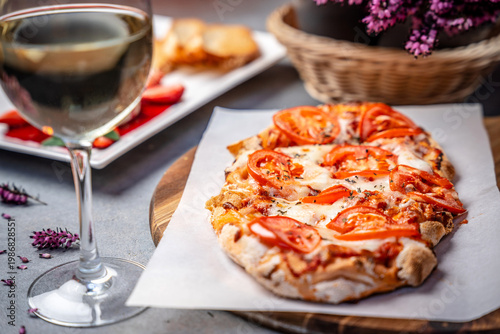 Homemade pizza with tomatoes cheese and wine
