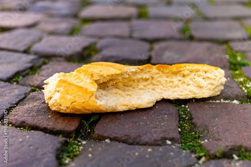 Crusty bread resting on cobblestones, nature reclaiming a forgotten snack in the warm afternoon sun