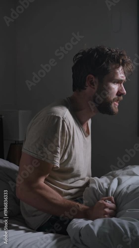 Man sitting in bed at night yelling from insomnia and distress, vertical shot