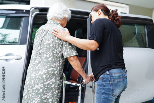 Caregiver help Asian elderly woman disability patient get in her car.