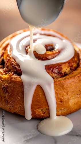 Freshly baked cinnamon roll with icing dripping on a marble surface