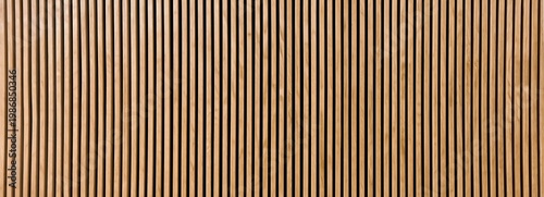 Close-up of a wooden panel with vertical slats in alternating light and dark tones, creating a striped pattern.