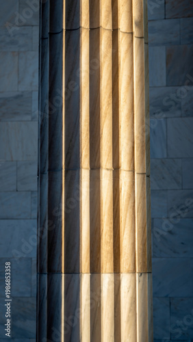Close-up of a marble column with golden light reflection.