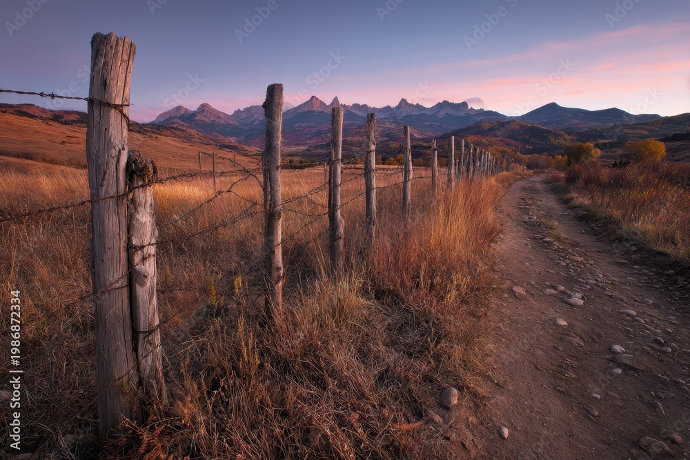 Fototapeta premium Golden hour landscape in southwest Colorado: rustic fence, warm dawn light, and distant alpine peaks