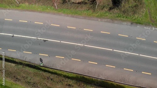 Person walking alone on rural road shoulder, highlighting pedestrian safety concerns and urban planning challenges.