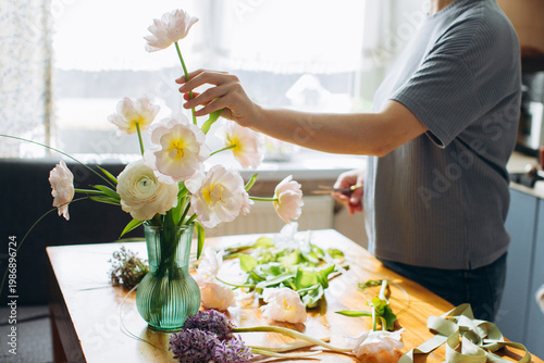 Woman arranging a fresh spring flower bouquet at home