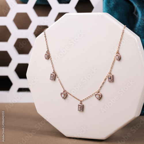 Canvas-taulu Exquisite rose gold necklace featuring heart and baguette-cut crystal charms on a white geometric stand