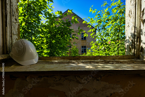 White Hard Hat on Windowsill of Abandoned Building with Broken Glass and Peeling Paint