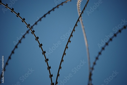 Ein Stacheldrahtzaun vor blauem Hintergrund.