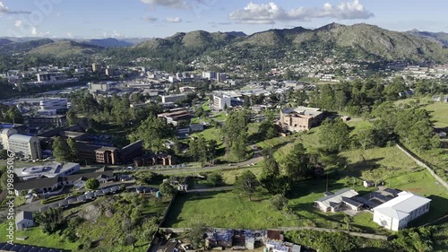 Drone flies backwards over highway outside city in the late afternoon before sunset in mountain town of Mbabane, Eswatini