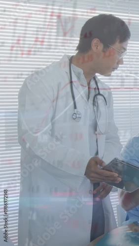 Vertical video: Doctor leaning to colleague tapping tablet and showing medical charts for review