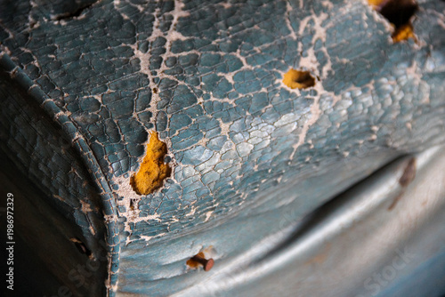 The blue leather surface of the sofa seat is old, cracked and torn so that the foam inside is visible