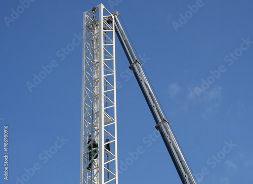 Crane installing new boom section at construction site