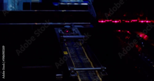 A close up view of automated machinery inserting components onto a circuit board during the manufacturing process. Robotic assembling microchip. Closeup shot.