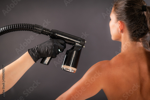 Foto Professional spray tan to the upper back with a handheld device