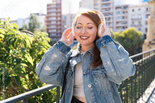 Foto Woman enjoying music with eyes closed, smiling while listening to audio on headp