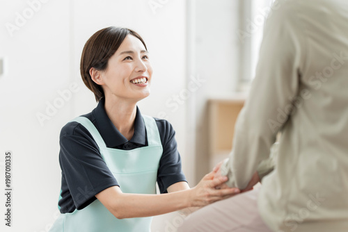 Fotografie 高齢者の手を握り、笑顔で話を聞く女性介護スタッフ