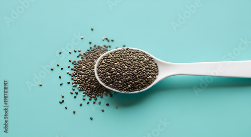 Spoon full of chia seeds with some scattered on a blue background