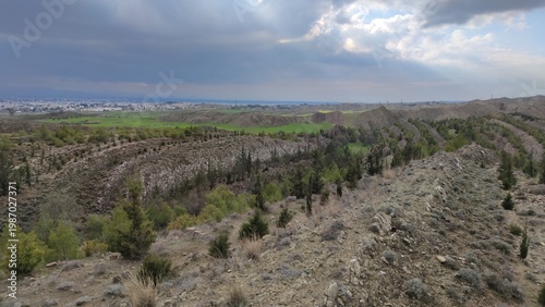 Tableau sur toile A high-angle view of a reforestation project in the Tashkent area of Northern Cyprus, featuring rows of young tree saplings planted across rocky ridges under a dramatic, overcast sky
