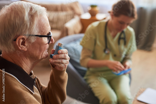 Photos Senior man using inhaler during respiratory care consultation in nursing home, n